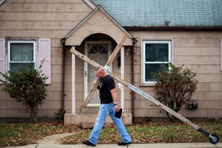 A man carries a cross through a neighborhood during Sunday church services in Ferguson, Missouri, November 30, 2014.