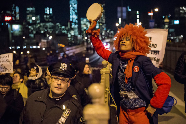 A female protester, demanding justice for Eric Garner, plays the tambourine as she and others enter Brooklyn over the Brooklyn Bridge in New York City December 4, 2014. Protesters swarmed streets of Manhattan and other cities for a second night of mostly peaceful rallies to denounce a New York grand jury's decision to spare a white police officer from criminal prosecution in the choking death of an unarmed black man. The reaction to Wednesday's decision not to indict officer Daniel Pantaleo for his role in the videotaped confrontation that left 43-year-old Eric Garner dead echoed a wave of outrage sparked nine days earlier by a similar outcome in the fatal shooting of an unarmed black teenager by a white policeman in Ferguson, Missouri.