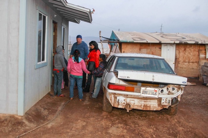 Members of a weekend outreach held during this Christmas season to migrant farm workers of Maneadero, Mexico, pray with Oaxacan family after gifts were delivered and the mother of the household had her feet washed as an act of Jesus' love, Dec. 6, 2014.