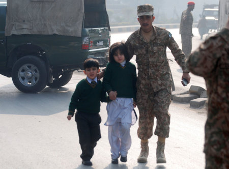 A soldier escorts schoolchildren from the Army Public School that is under attack by Taliban gunmen in Peshawar, December 16, 2014. Taliban gunmen in Pakistan took hundreds of students and teachers hostage on Tuesday in a school in the northwestern city of Peshawar, military officials said