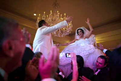 Megan Moshar (R), 26, who is of Persian, German and Filipino descent, dances with her husband George Safar, 27, whose parents are from Syria, as they are both lifted into the air during their wedding reception in Pasadena, California August 16, 2014.