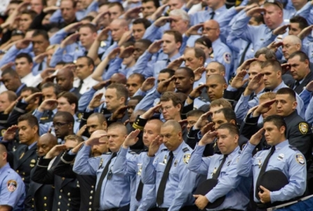 Firefighters stand and salute during a memorial service for their fallen comrades.