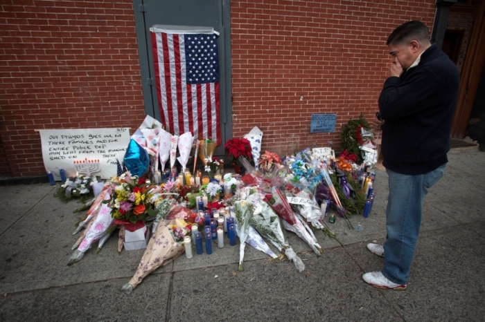 Miguel Esteves cries before placing his rosary beads on a makeshift memorial at the site where two police officers were shot in the head in the Brooklyn borough of New York, December 21, 2014. The officers, Wenjian Liu and Rafael Ramos were shot and killed as they sat in a marked squad car in Brooklyn on Saturday afternoon, New York Police Commissioner William Bratton said. The suspect in the shooting then shot and killed himself, Bratton said at a news conference at the Brooklyn hospital where the two officers were taken.