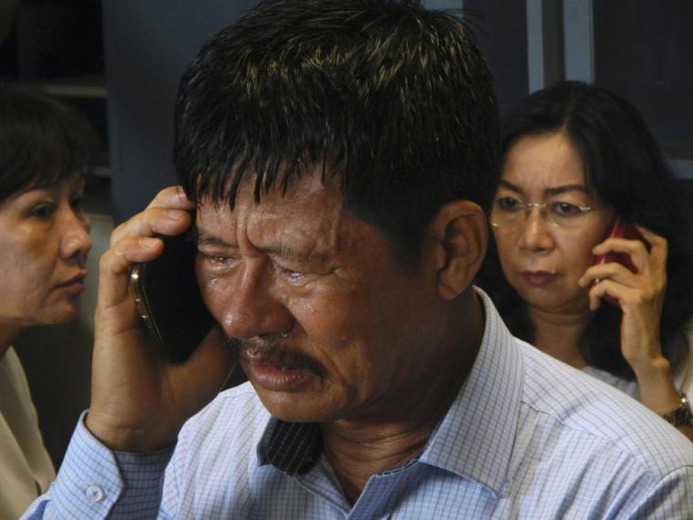 Family members of passengers on board AirAsia flight QZ 8501 talk on their phones while waiting for information inside a crisis center at Juanda Airport in Surabaya, Indonesia, December 28, 2014.