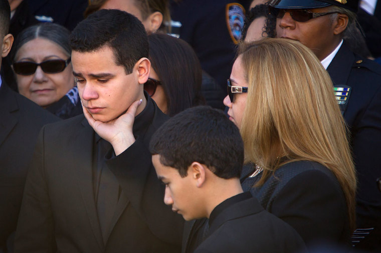 Widow Maritza Ramos touches her son Justin Ramos' face as her other son, Jaden Ramos, looks down as the casket of their father, slain NYPD officer Rafael Ramos, is loaded into a hearse during his funeral at Christ Tabernacle Church to it's final resting place in the Queens borough of New York December 27, 2014. Targeted for their uniform, Rafael Ramos and Wenjian Liu were slain last Saturday afternoon while sitting in their patrol car in Brooklyn in what is only the seventh instance of police partners being killed together in the city in more than 40 years. Thousands of police officers from departments around the country, including those in St. Louis, Atlanta, Boston, New Orleans and Washington, D.C., were expected to join U.S. Vice President Joe Biden and other officials for the funeral service at the church on Saturday.