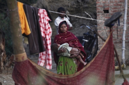 A woman holds her child as she stands outside her house at Dalit village of Bhaddi Kheda in the northern Indian state of Uttar Pradesh, January 15, 2012. Although she presides over one of the most poverty-plagued states of India -- its per-capita income is just above 50 percent of the national average -- Kumari Mayawati's extraordinary personal extravagance preserves a tradition set over the centuries by a succession of rulers in the plains of the river Ganges.