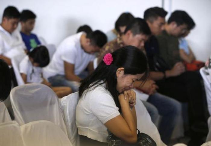 Family members of passengers onboard missing AirAsia flight QZ8501 pray at a waiting area in Juanda International Airport, Surabaya, Indonesia, December 30, 2014.