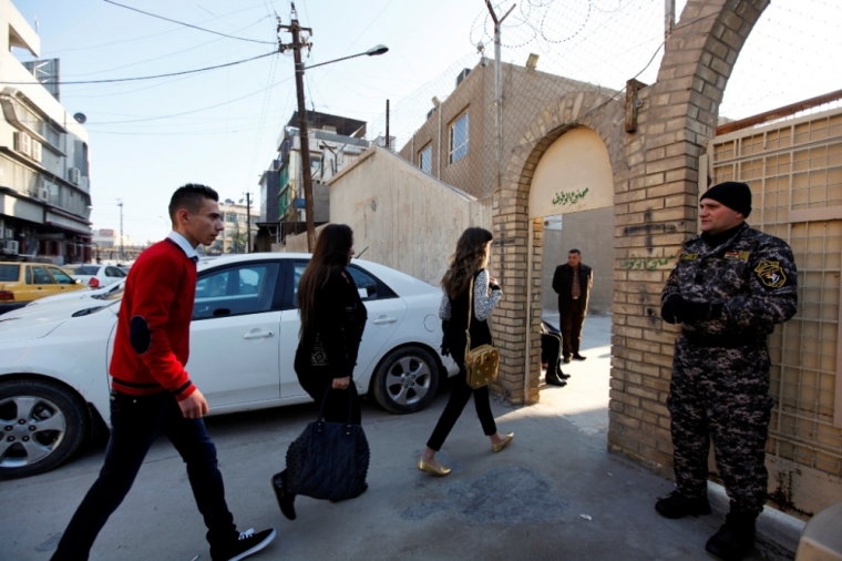 A member of the Iraqi security forces stands guards as Iraqi Christians attend a mass at Sacred Heart Catholic Church in Baghdad, December 25, 2014. Baghdad's embattled Christian community worshipped defiantly Wednesday night at Christmas Eve mass. The pews filled at Baghdad's Sacred Heart church, as people remembered the darkest year in memory.