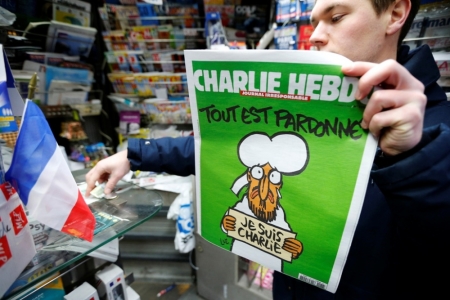 A man holds the new issue of satirical French weekly Charlie Hebdo entitled 'Tout est pardonne' ('All is forgiven'), which shows a caricature of the Muslim prophet Muhammad, in front of a kiosk in Paris January 14, 2015.