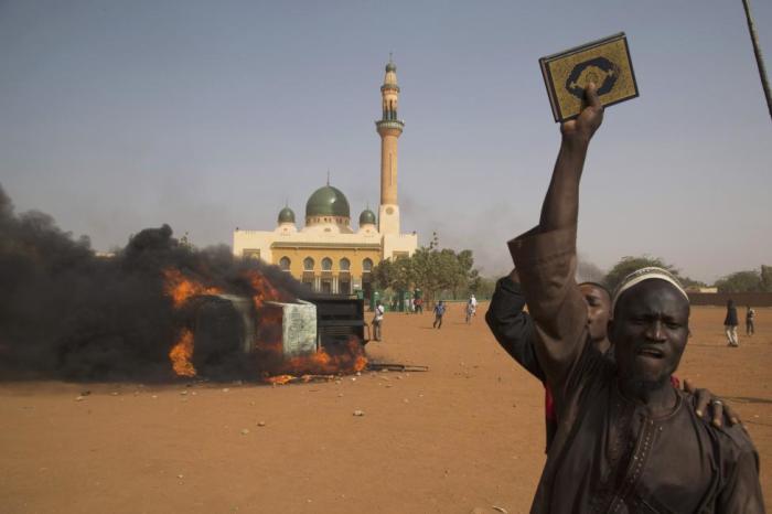 A man holds a copy of the Quran during a protest against Niger President Mahamadou Issoufou's attendance last week at a Paris rally in support of French satirical weekly Charlie Hebdo, which featured a cartoon of the Muslim prophet Muhammad as the cover of its first edition since an attack by Islamist gunmen in Niamey, January 17, 2015.