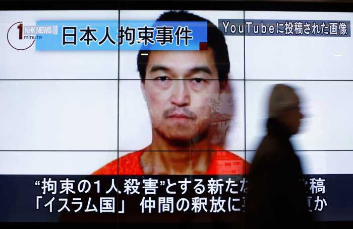 A man walks past screens displaying a television news programme showing an image of Kenji Goto, one of two Japanese citizens taken captive by Islamic State militants, on a street in Tokyo January 25, 2015. Japanese Prime Minister Shinzo Abe on Sunday called the apparent killing of Japanese captive Haruna Yukawa by Islamic State militants 'outrageous and impermissible,' and again called for the group to release Goto, the second Japanese national they are holding. The words on the screen read 'Japanese hostage incident' (top L) and 'a still image posted on YouTube' (top R).