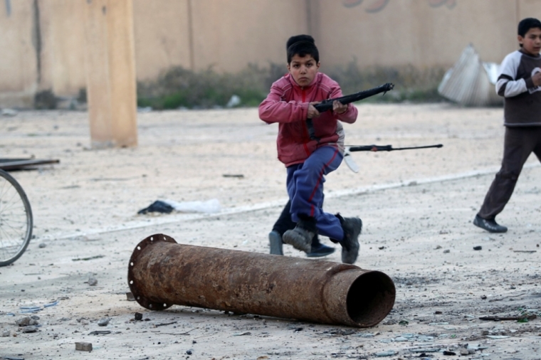 Children play with their toy weapons in a damaged school in Deir al-Zor, eastern Syria, February 21, 2014. Picture taken February 21, 2014.