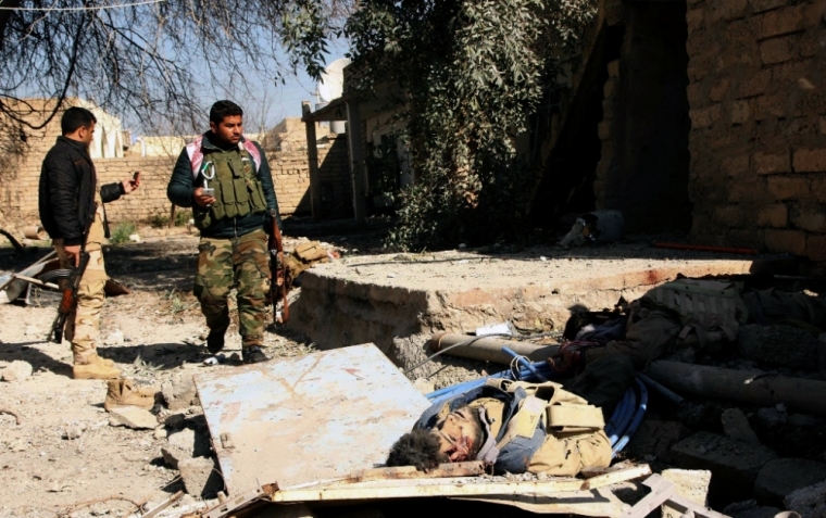 Kurdish Peshmerga fighters stand near the body of an Islamic State militant killed during a battle, on the outskirts of Mosul, Iraq, February 6, 2015.