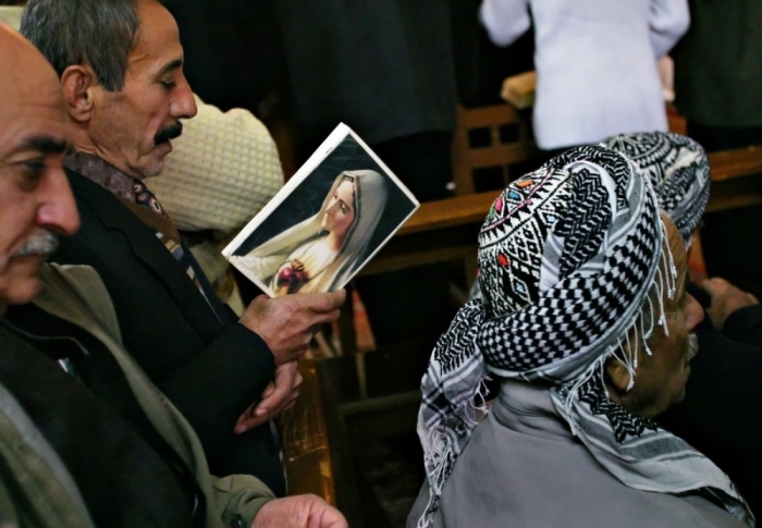 Iraqi Asyrian Christians, some wearing traditional Kurdish headgear, pray during the Christmas service in an Asyrian church in the northern city of Arbil, December 24, 2004. In spite of the security risks, the church was full of worshippers marking the most important Christian holiday of the year.