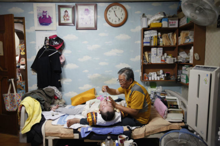 Pastor Lee Jong-rak feeds his 25-year-old son Lee Eun-man, who has cerebral palsy, at the Joosarang church in Seoul, South Korea, on Sept. 18, 2012.