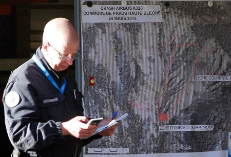 A French investigator stands in front of a map showing the crash site of a Germanwings Airbus A320 near Seynes-les-Alpes, in French Alps, March 27, 2015. A young German co-pilot barricaded himself alone in the cockpit of Germanwings flight 9525 and apparently set it on course to crash into an Alpine mountain, killing all 150 people on board including himself, French prosecutors said on Thursday. The pilot Andreas Lubitz, 27, who crashed a plane in the French Alps had received a sick note from doctors showing he suffered a health condition that would have prevented him flying the day of the crash, which he apparently hid from his employer, German prosecutors said.