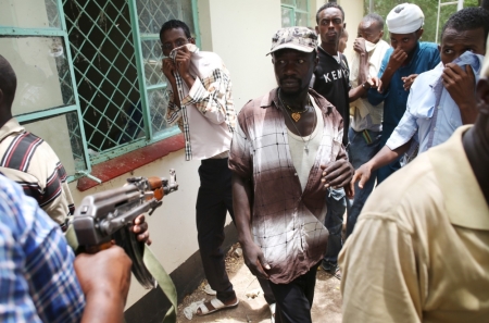 A policeman points his gun as he tries to push back people who came to see the bodies of suspected Garissa University College attackers in a morgue in Garissa, April 4, 2015. The death toll in an assault by Somali militants on Garissa University College is likely to climb above 147, a government source and media said on Friday, as anger grew among local residents over what they say as a government failure to prevent bloodshed.