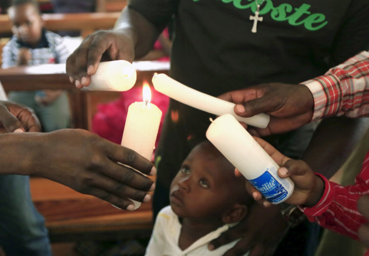 A boy looks on as church members light candles during an Easter Sunday service at the Catholic church in Garissa April 5, 2015.