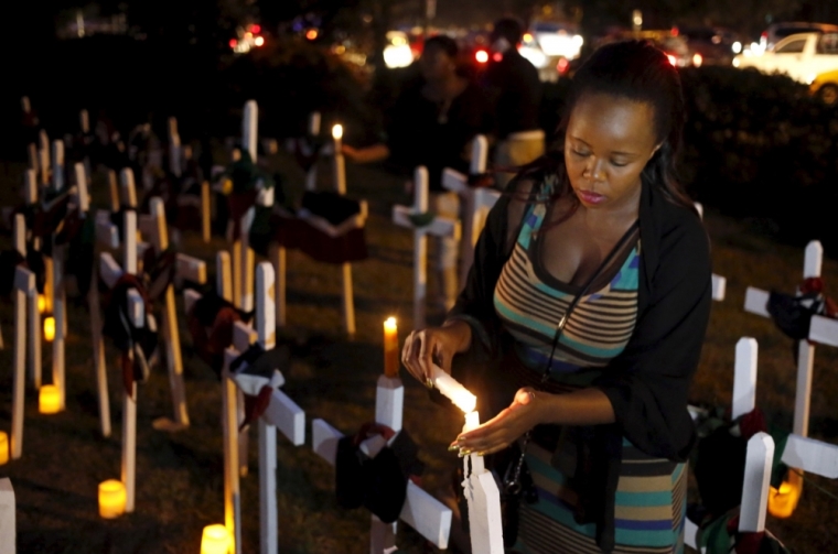 A woman lights a candle on a wooden cross during a memorial vigil for the people killed by gunmen at the Garissa University College, at the 'Freedom Corner' in Kenya's capital Nairobi, April 7, 2015. Kenyan university students marched in the capital on Tuesday to demand more security from the government after gunmen killed nearly 150 people at a campus in the eastern town of Garissa last week. A citizens group planned to hold a vigil in Nairobi's main park later in the evening, tapping growing public frustration over security in the wake of the attack claimed by al-Shabaab radical Islamists based in neighboring Somalia.