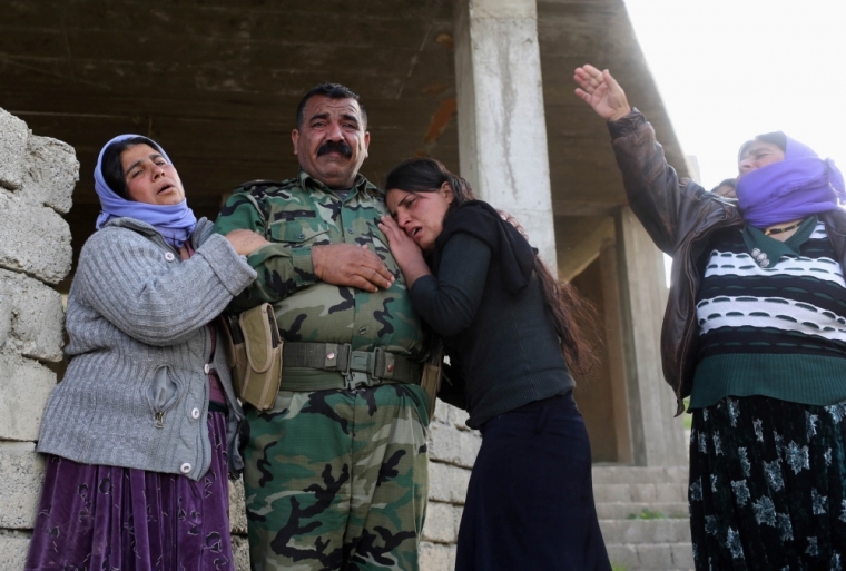 Kurdish Yazidis, relatives of a Peshmerga fighter killed in a suicide attack in Sinjar province, mourn with another relative, also member of the Peshmerga, before the burial ceremony at Mazar Sharaf Eldin, a sacred and cemetery area for the Yazidi minority, north of Sinjar, March 2, 2015. A number of Peshmerga were killed and others injured after two suicide car bombs attacks targeted a building the Peshmerga were using for fighting, according to Peshmerga officials.