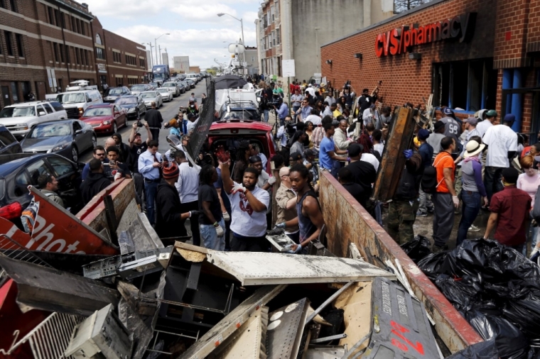 Members of the community work to clean up a recently looted and burned CVS store in Baltimore, Maryland, United States April 28, 2015. The day after rioters tore through Baltimore, the city's mayor was criticized on Tuesday for a slow police response to some of the worst U.S. urban unrest in years after the funeral of Freddie Gray, a 25-year-old black man who died in police custody. Maryland Governor Larry Hogan said he had called Mayor Stephanie Rawlings-Blake repeatedly Monday but that she held off calling in the National Guard until three hours after violence first erupted.