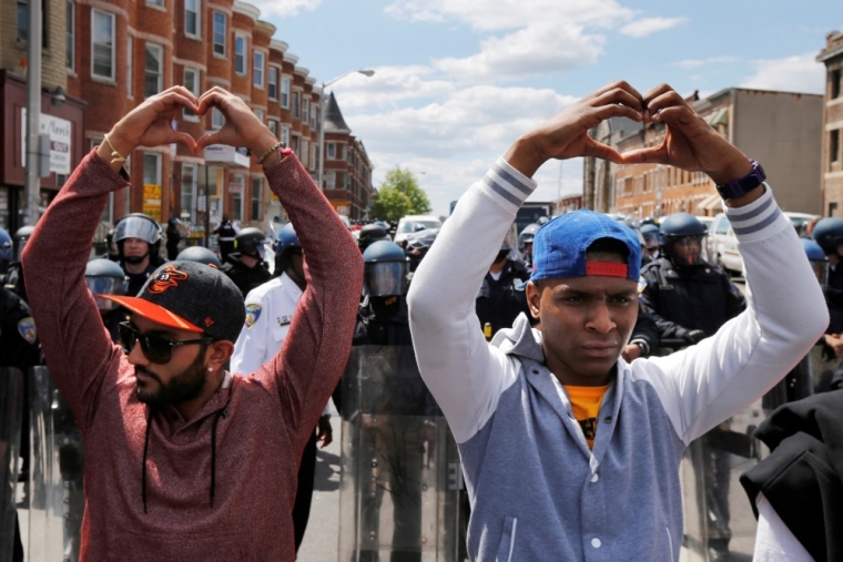 Members of the community make heart gestures with their hands in front of a line of police officers in riot gear, near a recently looted and burned CVS store in Baltimore, Maryland, April 28, 2015. The day after rioters tore through Baltimore, the city's mayor was criticized on Tuesday for a slow police response to some of the worst U.S. urban unrest in years after the funeral of Freddie Gray, a 25-year-old black man who died in police custody. Maryland Governor Larry Hogan said he had called Mayor Stephanie Rawlings-Blake repeatedly Monday but that she held off calling in the National Guard until three hours after violence first erupted.