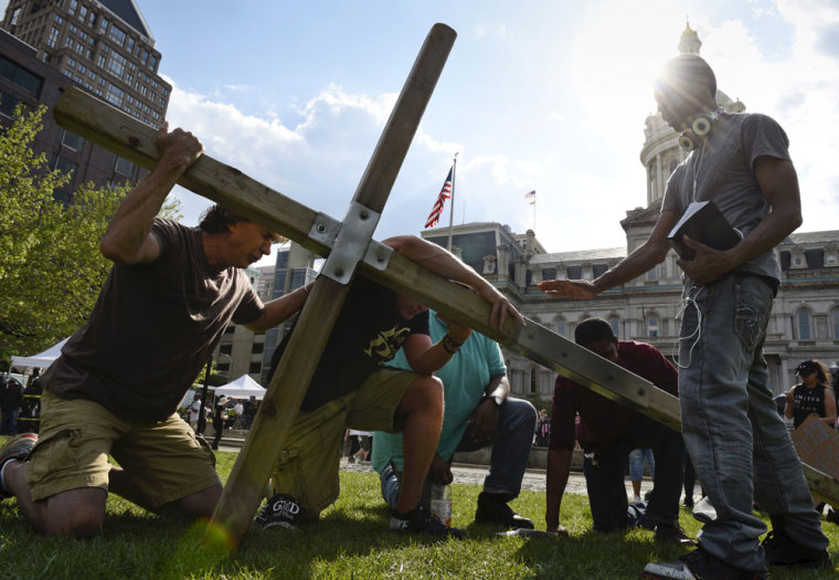 Men pray together during a religious rally for Freddie Gray in front of the City Hall in Baltimore, May 3, 2015. Baltimore's Mayor Stephanie Rawlings-Blake on Sunday lifted a 10 p.m. to 5 a.m. curfew she had imposed on the city last week after a night of looting and arson that followed the death of 25-year-old Freddie Gray from injuries suffered while in the police custoday. Hogan called for a day of prayer and reconciliation on Sunday.