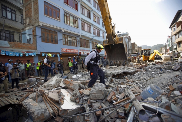 A U.S. rescue team member walks above debris in search for survivors after the earthquake in Kathmandu, May 12, 2015. A fresh 7.3-magnitude earthquake struck Nepal on Tuesday, killing more than two dozen people in the Himalayan country and neighboring states, as many buildings already weakened by a much bigger quake last month were brought down. The earthquake was centered 68 kilometers (42 miles) west of the town of Namche Bazaar, close to Mount Everest and the border with Tibet, the U.S. Geological Survey said. It could be felt as far away as northern India and Bangladesh.