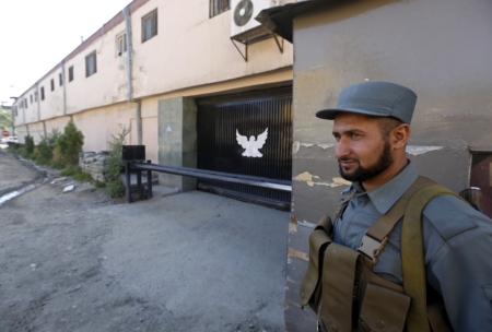 An Afghan policeman guards the gate of a guest house after an attack in Kabul, May 14, 2015. At least one gunman attacked the guest house popular with foreigners in Kabul on Wednesday killing at least five people, including an American and two Indians, in a bold assault that showed Afghanistan still faces security challenges.