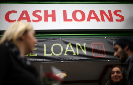 Pedestrians pass by a lending shop in northeast London October 3, 2013. Britain's financial watchdog drew fire on Thursday for failing to impose a cap on the huge interest rates imposed by payday lenders as it set out its plan to discipline the industry.