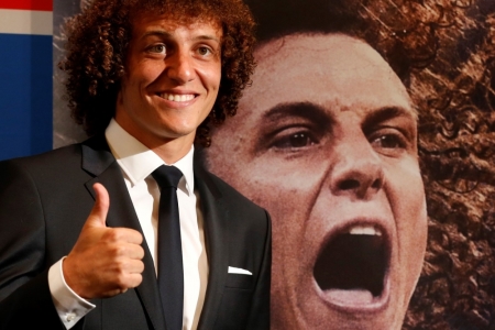 Brazil's soccer player David Luiz, newly-signed player for French soccer club Paris St. Germain, poses beside a poster of himself after a news conference at the Peninsula Paris luxury hotel in Paris, August 7, 2014. Luiz has signed a five year contract with the French Ligue 1 champions Paris St Germain.