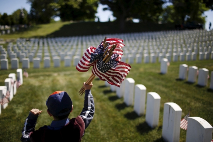 A member of the Boy Scouts of America holds flags to be placed at graves at Cypress Hills National Cemetery in Brooklyn, New York, May 23, 2015. The annual 'Flags-In' ceremony is held ahead of Memorial Day to honor the nation's fallen members of the military.