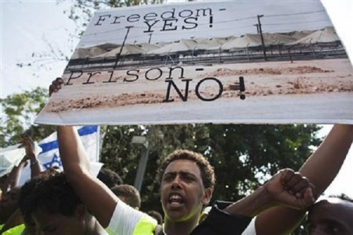 An African migrant from Eritrea holds a placard during a protest near the Ministry of Defence in Tel Aviv October 18, 2012.