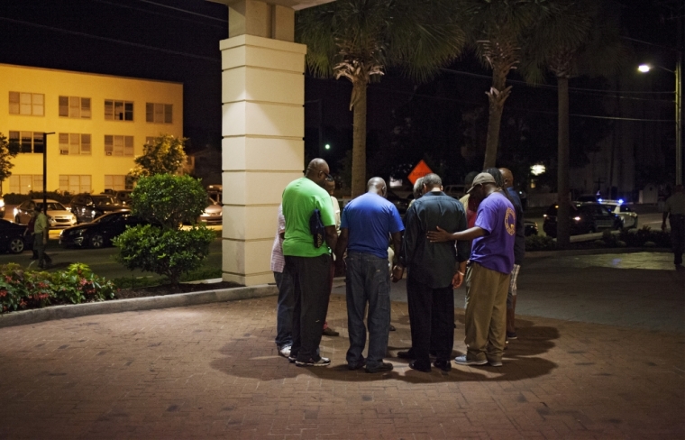 A small prayer circle forms nearby where police are responding to a shooting at the Emanuel AME Church in Charleston, South Carolina, June 17, 2015. A gunman opened fire on Wednesday evening at the historic African-American church in downtown Charleston.