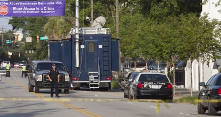 A Charleston police officer walks past the entrance of the Emanuel African Methodist Episcopal Church in Charleston, South Carolina, June 18, 2015. Police in Charleston were searching for a white gunman on Thursday who killed nine people in a historic African-American church, in an attack that police and the city's mayor described as a hate crime.