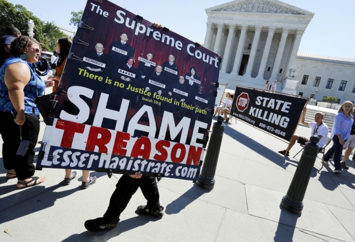 A protester, angry with the U.S. Supreme Court's decision last week that the U.S. Constitution provides same-sex couples the right to wed, carries a sign in front of the court building in Washington June 29, 2015. County clerks in Texas who object to gay marriage can refuse to issue marriage licenses to same-sex couples despite last week's landmark U.S. Supreme Court ruling requiring states to allow same-sex marriage, Texas Attorney General Ken Paxton said on Sunday.