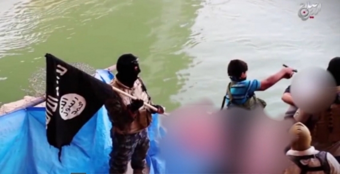 An alleged child executioner is seen standing over a prisoner in video footage released by ISIS in July 2015.