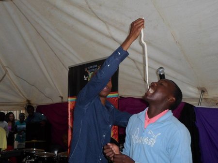 Self-styled South African prophet Penuel Mnguni (l) feeds a snake to one of his congregants.