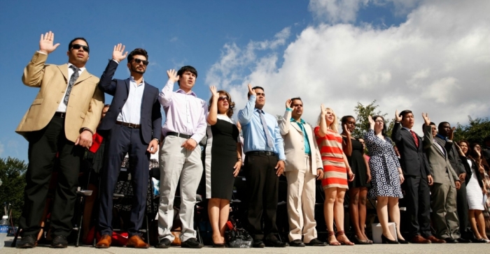 New U.S. citizens raise their hands as they take an oath of allegiance.