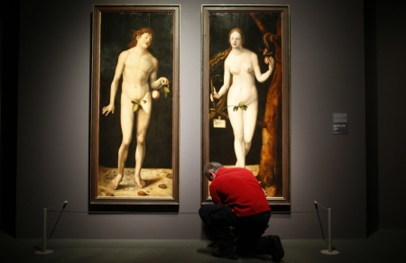 A museum worker cleans the floor in front of true to scale copies of the paintings 'Adam' and 'Eve' by Hans Baldung Grien, the apprentice of German Renaissance painter Albrecht Duerer, during a pre-view of the Duerer exhibition at the Staedel museum in Frankfurt October 22, 2013. 