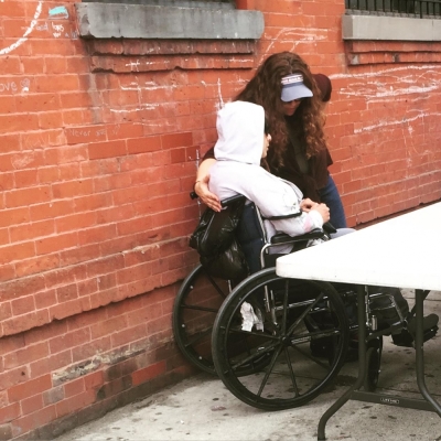 A volunteer offers prayer and food to a homeless person with special needs in New York City.