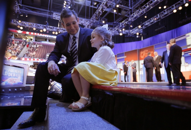 Republican 2016 U.S. presidential candidate and U.S. Senator Ted Cruz sits on the edge of the stage with his young daughter Catherine during a commercial break at the first official Republican presidential candidates debate of the 2016 U.S. presidential campaign in Cleveland, Ohio, August 6, 2015.