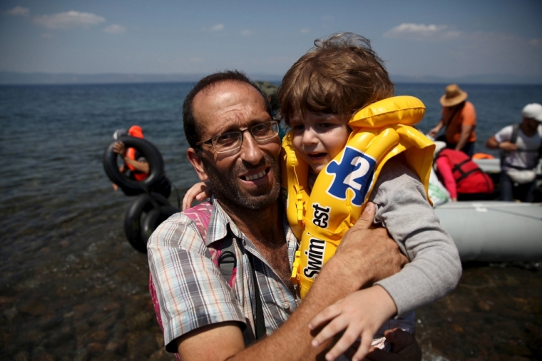 Syrian refugee Mustafa Mohammad embraces a boy after arriving on a dinghy at the Greek island of Lesbos August 6, 2015. The U.N refugee agency, UNHCR, estimates that Greece has received more than 107,000 refugees and migrants this year, more than double its 43,500 intake of 2014.