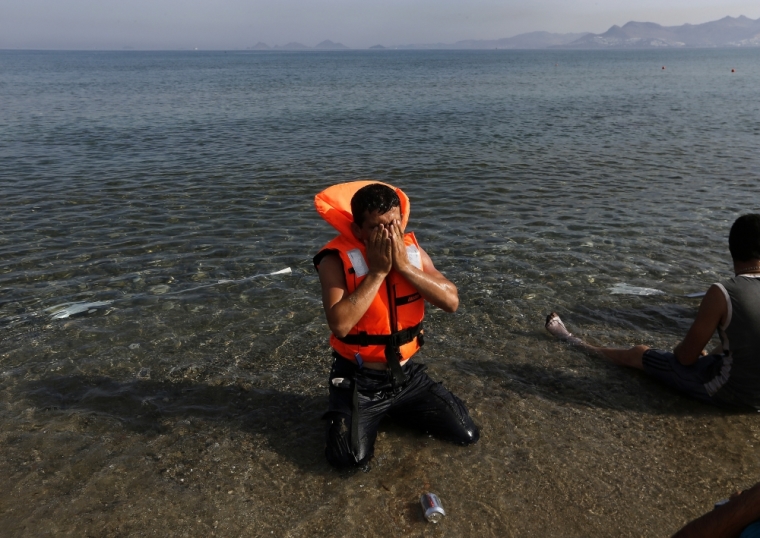 An Iranian migrant prays moments after arriving with another six family members by paddling an engineless dinghy from the Turkish coastat a beach on the Greek island of Kos August 15, 2015. United Nations refugee agency called on Greece to take control of the 'total chaos' on Mediterranean islands, where thousands of migrants have landed. About 124,000 have arrived this year by sea, many via Turkey, according to Vincent Cochetel, UNHCR director for Europe.