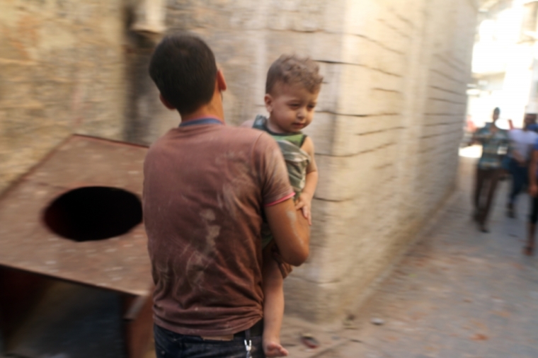 A man holds a child who survived what activists said was a ground-to-ground missile attack by forces of Syria's President Bashar al-Assad at the old city of Aleppo, Syria July 27, 2015.