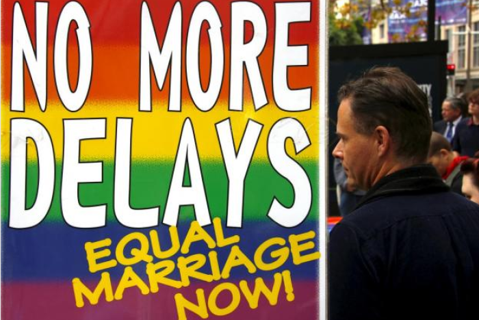 An activist stands beside a a banner as he listens to speeches during a rally supporting same-sex marriage in Sydney, Australia May 31, 2015.