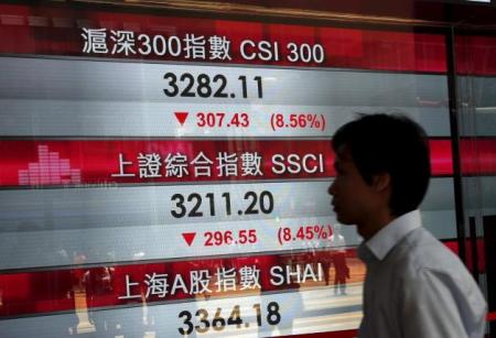 A passerby walks past a panel displaying China stock indexes at the financial Central district in Hong Kong, China August 24, 2015.