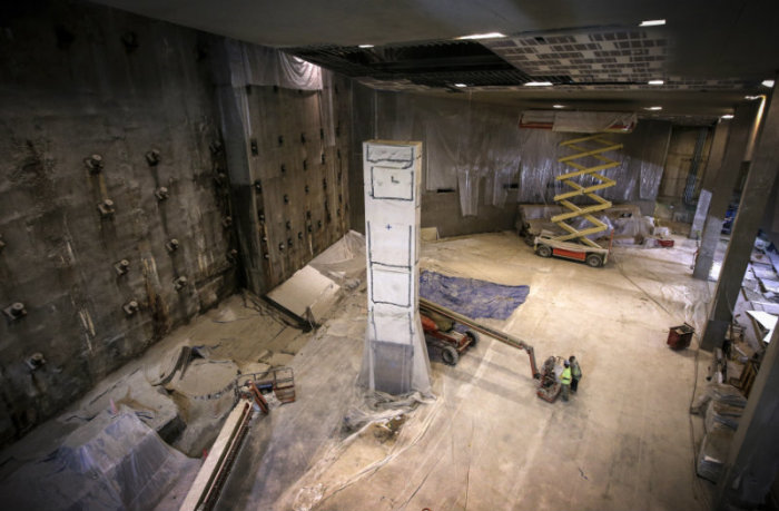 Construction continues around the last column of steel removed from the World Trade Center site in 2002, inside the 911 Memorial Museum, which is under construction, at the World Trade Center site in New York, July 2, 2013. The column (seen covered with protective material) is covered with messages and mementos of tribute affixed to its surfaces by recovery workers, first responders and family members of victims and will stand in this area of the Museum next to the 'Slurry Wall' (L) part of the World Trade Center's original foundation built to keep the Hudson River from flooding the site.