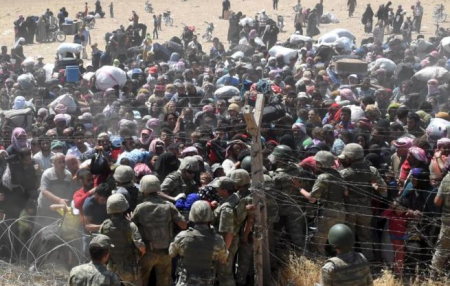 Soldiers help refugees get into Turkey as they flee the battle between the ISIS and Kurdish forces.