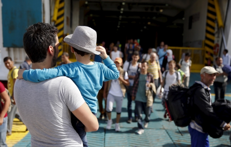 A Syrian refugee holds his son and waits for others to disembark from the Eleftherios Venizelos passenger ship at the port of Piraeus, near Athens, Greece, September 10, 2015. Most of the people flooding into Europe are refugees fleeing violence and persecution in their home countries who have a legal right to seek asylum, the United Nations said on Tuesday.